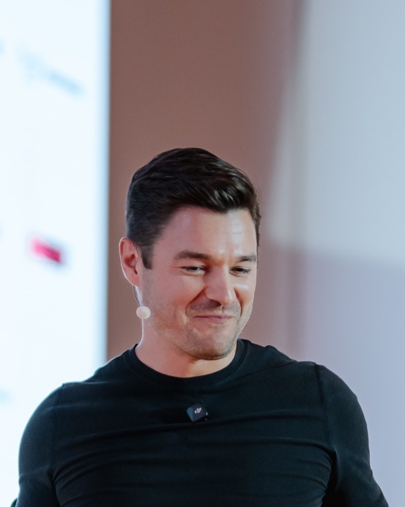 Nathan Latka smiling during a keynote talk